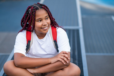 Smiling teen girl sitting with her legs crossed and looking contentedの写真素材