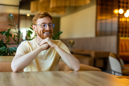 Ginger bearded man in casual outfit seated indoors smiling warmlyの写真素材