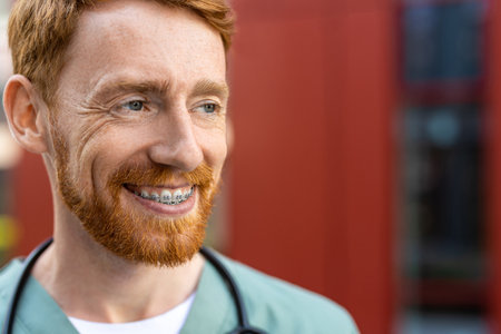 Ginger-haired man doctor looking away with positive expressionの写真素材