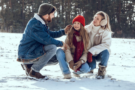 Happy family enjoying snowy weather in the forest and having fun togetherの写真素材
