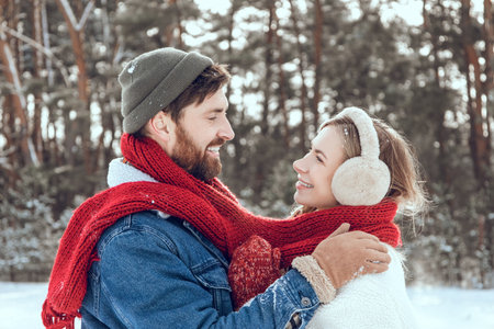 Man and woman looking romantic while having a walk in a winter forestの写真素材