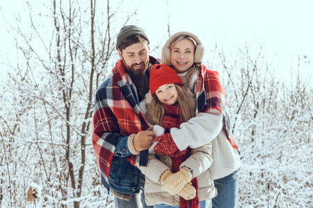 Happy and enjoyed young family spending time in a winter forest