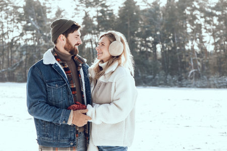 Two people spending a day in a winter forest and looking enjoyed and romantic
