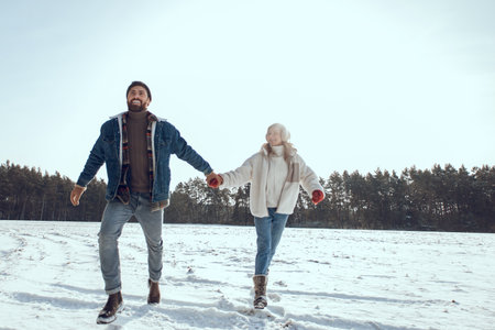 Happy couple running in a winter park and feeling excited and enjoyed