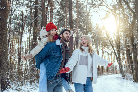 Young cute family enjoying a sunny winter day in a forestの写真素材