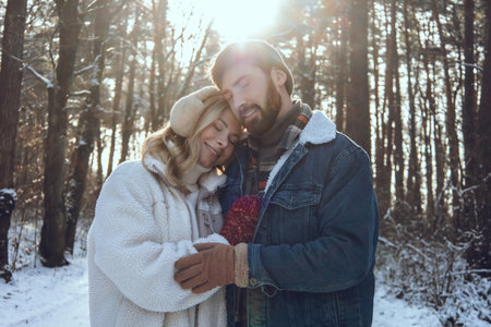 Young couple spending time together in a winter forest and looking romantic