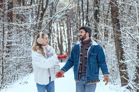 Young couple enjoying a walk in a winter forest and looking happy