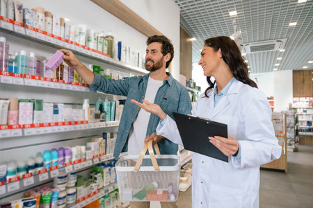 Healthcare professional giving advice to man with shopping basket inside drugstoreの写真素材