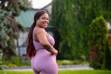 Cute african american young woman in pink sportswear looking happyの写真素材