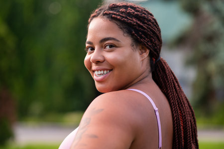 Cute african american young woman in pink sportswear looking happyの写真素材