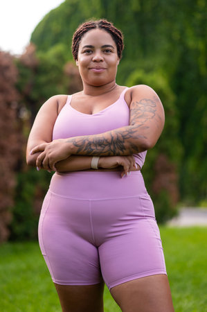Plus size young woman with a tattoo on her arm in pink sportswear