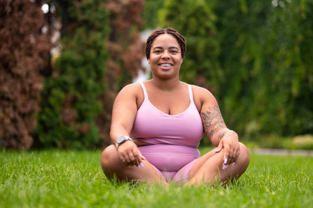 Woman in pink sportswear sitting on a grass on lotus pose and feeling good