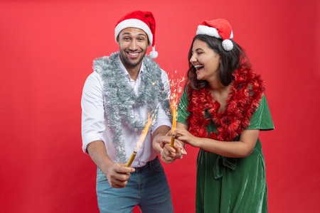 Family wearing Santa hats with bright tinsel celebrating Christmas eve together holding sparklersの写真素材