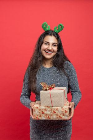 Woman in reindeer headband celebrating New Year event holding giftsの写真素材