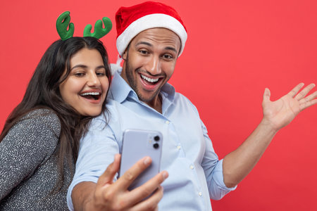 Happy man and woman taking selfie during Christmas celebration using smartphone for festive photoの写真素材