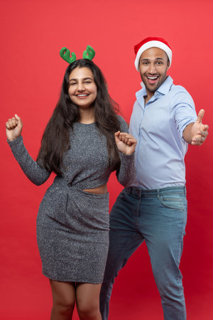 Couple man and woman wearing Santa hat and deer horns dancing while celebrating Christmas partyの写真素材