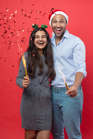 Joyful woman and man enjoying New Year celebration together holding festive sparklingsの写真素材