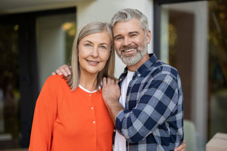 Portrait of senior couple smiling together outdoors near new houseの写真素材