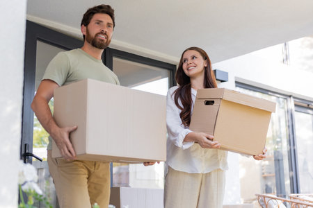 Couple carrying cardboard boxes while moving to a new house