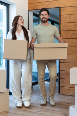Man and woman carrying boxes into a new accommodation and feeling excited