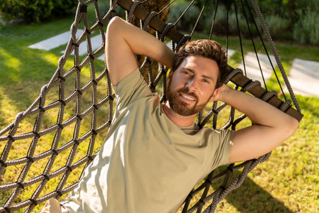 Bearded young man lying in a hammock and feeling relaxedの写真素材