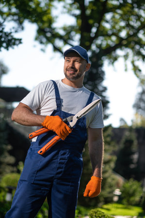 Worker wearing gloves and cap maintaining plants