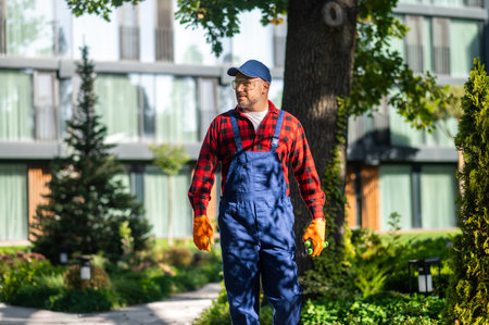 Portrait of gardener holding trimming equipment in well-kept garden