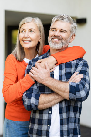 Senior man and woman together near their house looking happy and contentedの写真素材