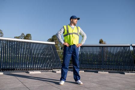 Engineer standing proudly on building rooftop with solar equipment