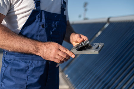 Worker standing near modern solar energy equipment on roofの写真素材