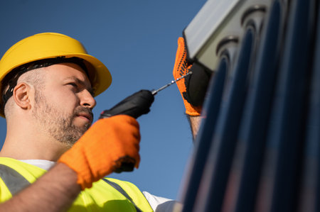 Technician wearing gloves inspecting solar power tubes on roofの写真素材