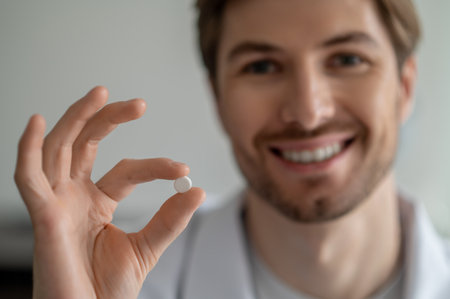 Close-up of smiling mans hand holding small white pillの写真素材