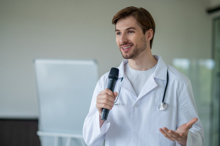 Male medical male presenting information at flipchart using microphone in clinicの写真素材