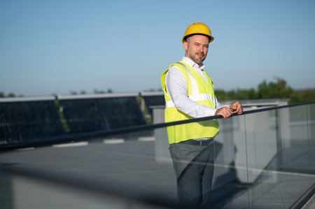 Engineer posing near solar panels on rooftop outdoors