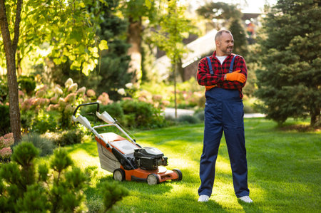 Gardener posing with lawnmower in backyard area