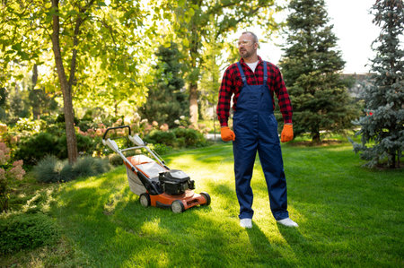 Man wearing overalls and gloves working outdoors in park areaの写真素材