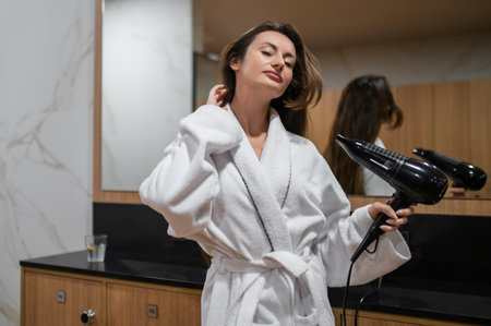 Long-haired caucasian young woman in white robe drying her hairの写真素材