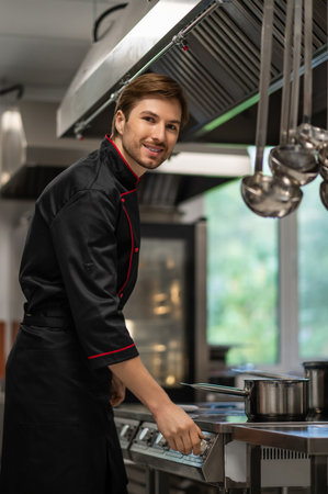 Skilled man working in restaurant standing near stove in culinary spaceの写真素材