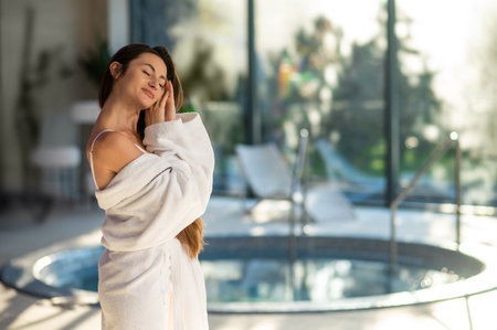 Woman in white bath robe standing near the pool in a spa centerの写真素材