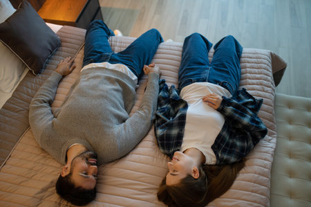 Young couple lying on the bed in a hotel room and feeling relaxedの写真素材