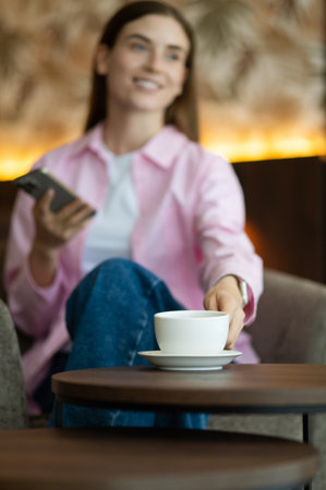 Young woman in pink with a phone in hands having teaの写真素材