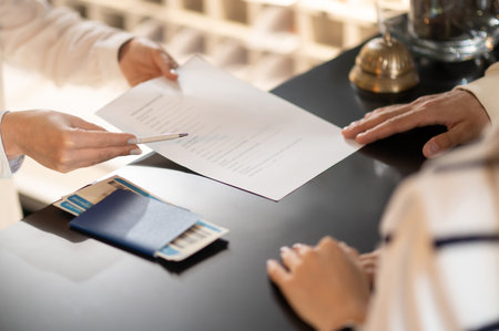 Close up picture of hands passing documents on a reception deskの写真素材