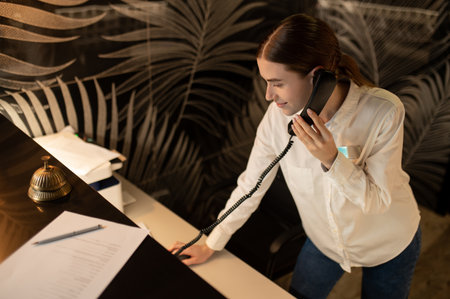 Receptionist talking on the phone while arranging accommodation for the customerの写真素材
