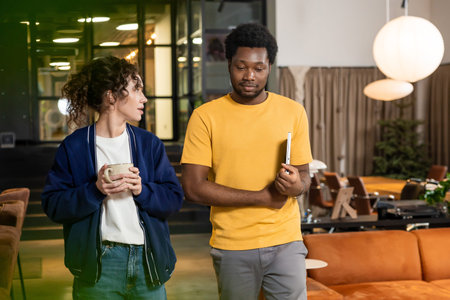 Young woman and man colleague discussing project standing in coworking interior