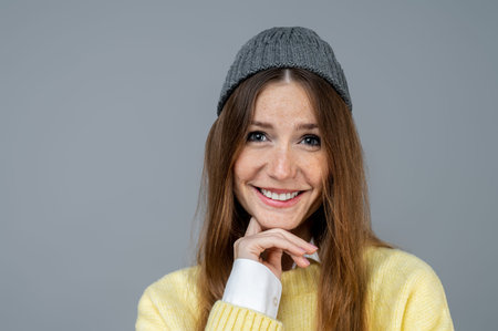 Waist up of a smiling cute young woman in grey hat