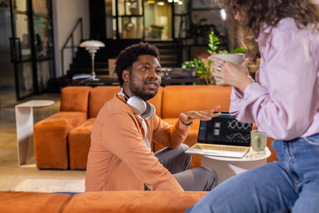 Businesswoman holding coffee talking with man during work discussion
