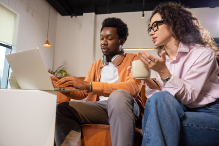 Wavy haired woman and man with laptop working together