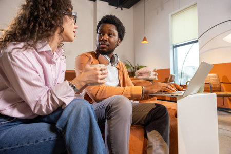 Businesswoman holding coffee talking with man during work discussion