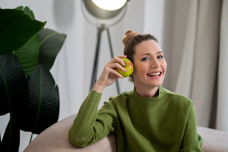Young smiling woman in green with apple in hand