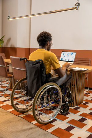 Man in wheelchair working attentively on laptop with migration analytics